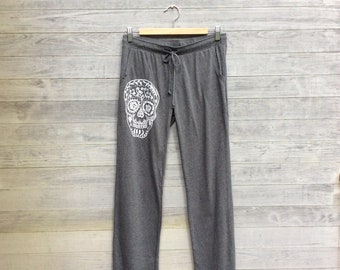 May include: Grey sweatpants with a white sugar skull design on the left leg.