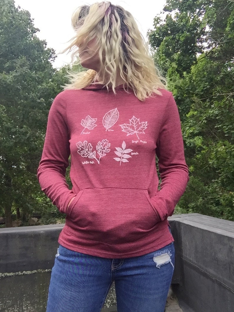May include: A maroon hoodie with a white outline of five different leaves. The leaves are labeled with their names: "Pepper", "Elm", "Sugar Maple", "White Oak", and "Ash".