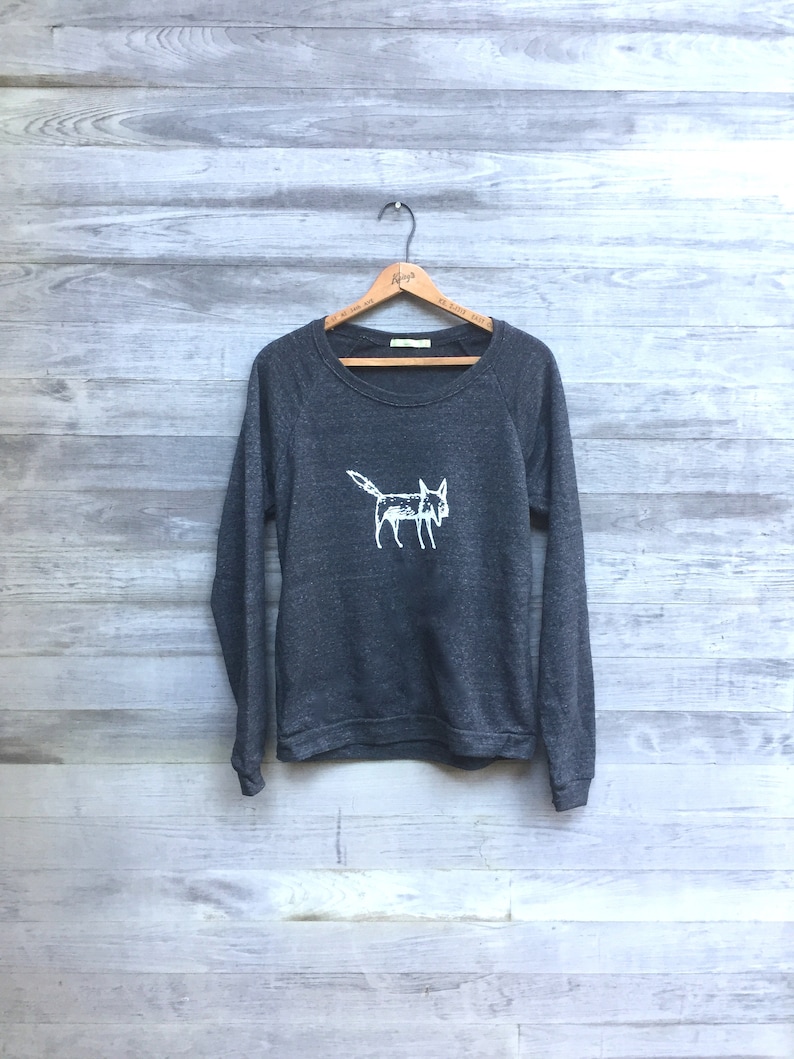 May include: A dark gray sweatshirt with a white graphic of a stylized fox on the front.