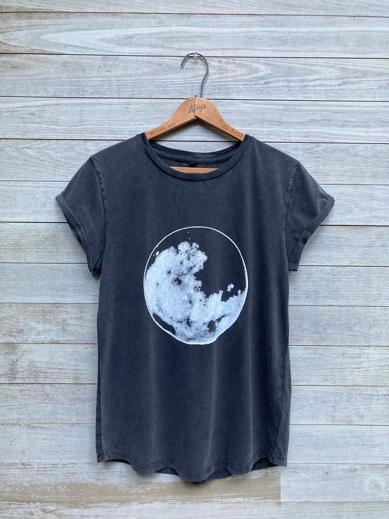 K&ouml;nnte beinhalten: Ein dunkelgraues T-Shirt mit einem wei&szlig;en Mondmotiv auf der Vorderseite.
