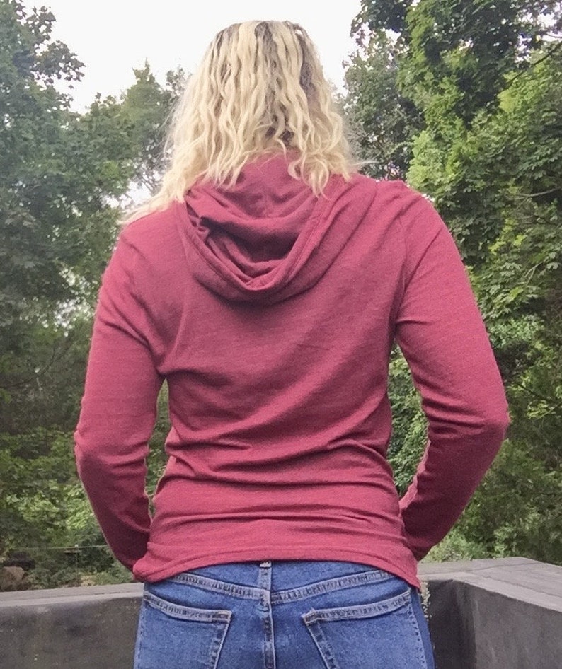 May include: A maroon long-sleeved hooded shirt with a fitted silhouette. The shirt is made of a soft, comfortable fabric and has a relaxed, casual look.