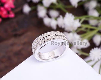 Puede incluir: Un anillo de plata con dos filas de pequeñas piedras preciosas transparentes. El anillo tiene una banda ancha y un acabado pulido. El texto "Royal Jewellery" es visible en el anillo. El anillo se muestra sobre una superficie blanca.