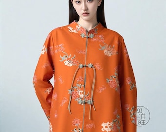 May include: Orange jacket with floral embroidery. The jacket features a mandarin collar and frog closures. The sleeves are long, and the jacket is adorned with a pattern of flowers and leaves.