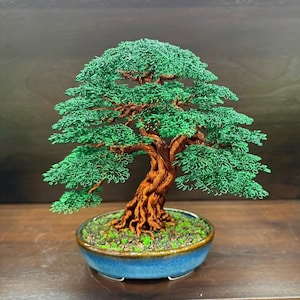 May include: A handcrafted wire bonsai tree sculpture. The tree features a detailed brown trunk and vibrant green foliage, set in a blue ceramic pot. The bonsai is a decorative piece, perfect for home or office decor.