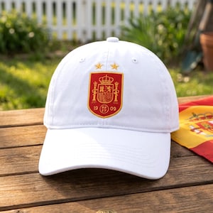 Puede incluir: Una gorra de béisbol blanca con un escudo bordado en rojo y oro en el panel frontal. El escudo muestra una corona, columnas y el texto 19 RFEF 09, coronado por dos estrellas doradas. La gorra tiene una corona estructurada y visera curva.