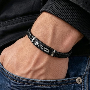 Könnte beinhalten: Ein schwarzes Armband aus geflochtenem Leder mit medizinischem Warnhinweis, bestehend aus einer rechteckigen Metallplatte mit silbernem Stern des Lebens und der Gravur Leah-Epilepsy ICE:920.369.5125, befestigt mit silberfarbenen Metallelementen.