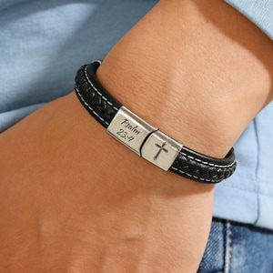 May include: Black leather bracelet with white stitching and a silver clasp. The clasp features the text "Psalm 23:4" and a cross symbol. The bracelet is worn on a wrist.