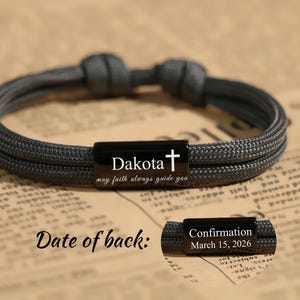 May include: A gray braided bracelet with a black rectangular clasp engraved with the name "Dakota", a cross, and the phrase "may faith always guide you". A second clasp reads "Confirmation March 15, 2026".