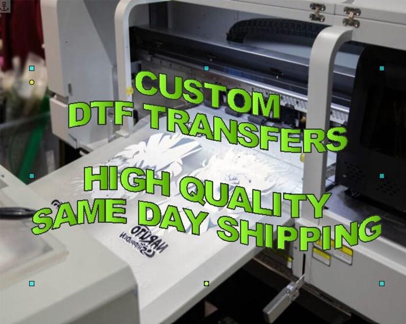 May include: A large white printer with the text "CUSTOM DTF TRANSFERS HIGH QUALITY SAME DAY SHIPPING" in green. The printer is printing a white design onto a white surface. The image is well-lit and shows the details of the printing process.