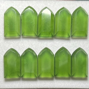 May include: Ten translucent, light green gemstones cut into a shield or coffin shape with a flat base and a pointed top. The stones are arranged in two horizontal rows of five, each displaying a smooth, polished surface and uniform color.