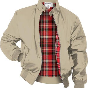 May include: A tan bomber jacket with a red, black, and white plaid lining. The jacket has a zip-up front, a buttoned collar, and ribbed cuffs and hem. The label reads "MEGA JUMBLE".