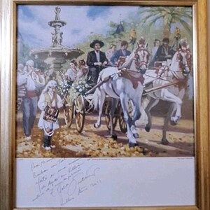 May include: A framed painting shows a procession with white horses drawing a carriage. A man in a black hat is in the carriage, and people in traditional dress walk alongside. A fountain and palm trees are in the background. The painting is signed.