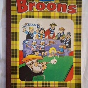 May include: A vintage copy of "The Broons" comic book. The cover has a yellow and black tartan pattern with the title in red. The illustration shows cartoon characters, some with scarves, watching a football match.
