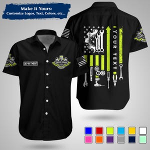 May include: Black mechanic's shirt with a design featuring tools, gears, and an American flag motif. The shirt includes the text "YOUR TEXT" and "DEPARTMENT". The design incorporates green and white accents. The shirt is short-sleeved.