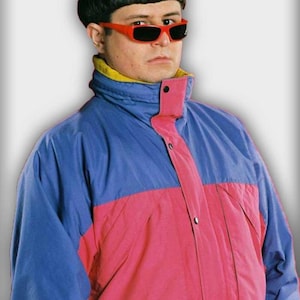 May include: A person with a dark bowl-cut hairstyle wearing bright red sunglasses and a colour-blocked jacket. The jacket features a blue upper section, a pink lower section, and a yellow inner collar, secured with a front placket and black buttons.