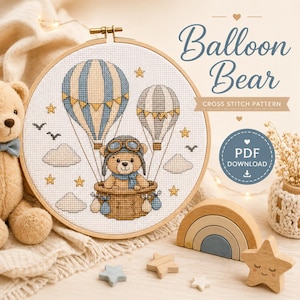 Può includere: Un modello a punto croce intitolato "Balloon Bear" presenta un orsacchiotto in mongolfiera con strisce blu e beige. Il disegno è incorniciato in un cerchio di legno, con stelle e nuvole. È visibile anche la scritta "PDF DOWNLOAD".
