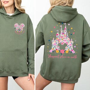 May include: Olive green hoodie with a front pocket and a hood. The front features a floral Mickey Mouse head design. The back displays a floral castle design with the text "Happiest place on earth".
