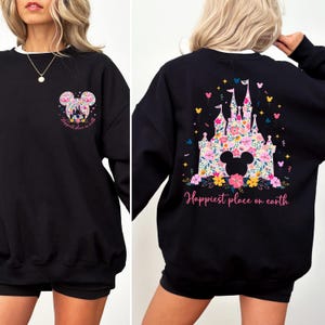 May include: Black sweatshirt with a white collar featuring a floral Mickey Mouse design on the front and back. The back design includes a castle and the words "Happiest place on earth".