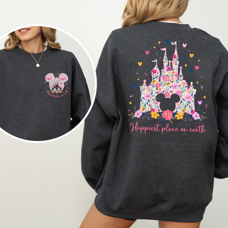 May include: Dark gray sweatshirt featuring a floral Mickey Mouse design on the front and back. The back design showcases a castle with floral accents and the text "Happiest place on earth" in pink.