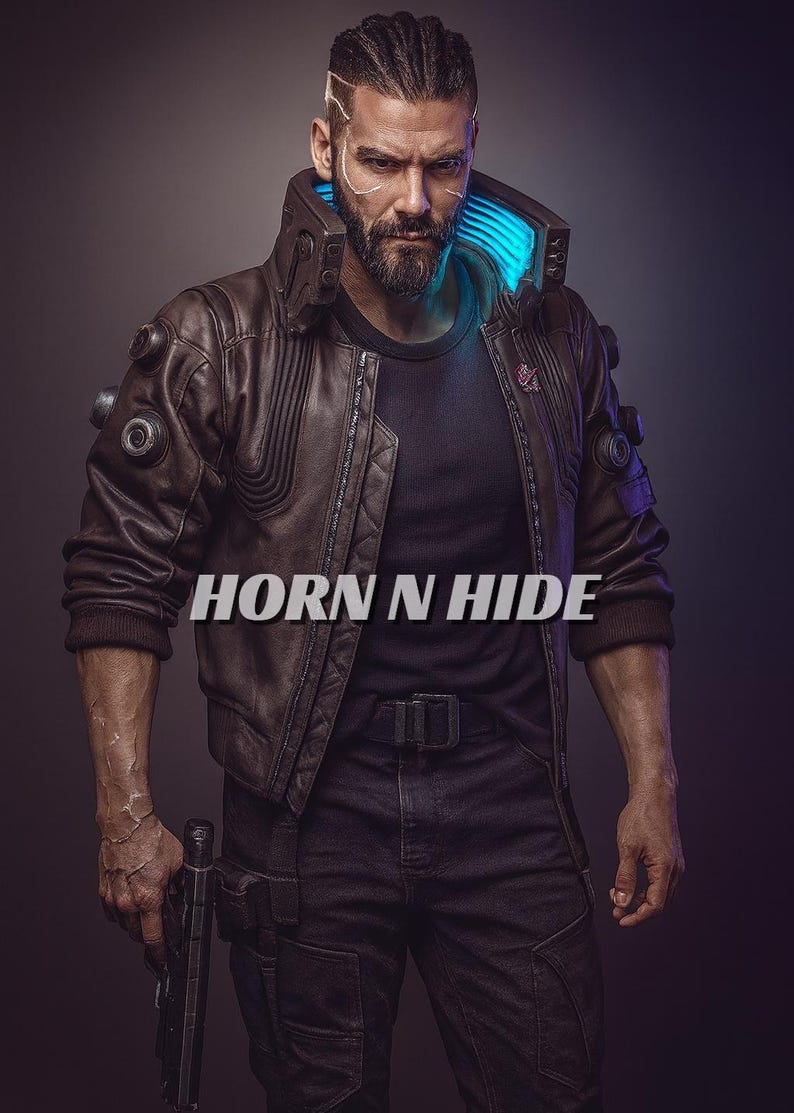 Pu&ograve; includere: Giacca di pelle marrone con design trapuntato, indossata sopra una maglietta nera e jeans scuri. La giacca ha un colletto alto con accenti al neon blu. L'immagine include il testo "HORN N HIDE".