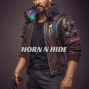 Pu&ograve; includere: Giacca di pelle marrone con colletto alto e molteplici elementi decorativi. La giacca presenta una toppa "SAMURAI" e il testo "HORN N HIDE" &egrave; visibile. La persona tiene in mano una pistola nera.