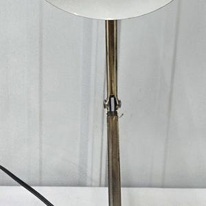 May include: A vintage desk lamp with a white shade and a brown top. The lamp has a brass-colored adjustable arm and a wooden base with the brand name "tenson" and an off/lo/hi switch.