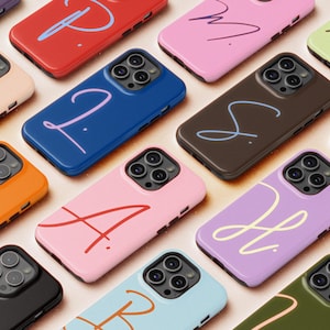May include: A selection of brightly coloured phone cases, each featuring a different hue and a handwritten initial. The cases come in shades like pink, blue, orange, and purple. The initial is in a contrasting colour, offering a personalised feel.