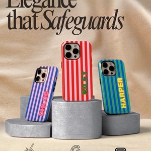 May include: Three personalised phone cases with vertical stripes in red, blue, and green, each with a different name. The cases are displayed on grey geometric blocks. The text "Elegance that Safeguards" is at the top.