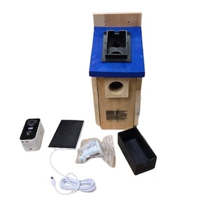 Puede incluir: Una casa para p&aacute;jaros de madera con techo azul y un orificio de entrada redondo. La casa para p&aacute;jaros va acompa&ntilde;ada de una c&aacute;mara, un panel solar, accesorios de montaje y una bandeja negra. La casa para p&aacute;jaros tiene un peque&ntilde;o dise&ntilde;o de bandera estadounidense.