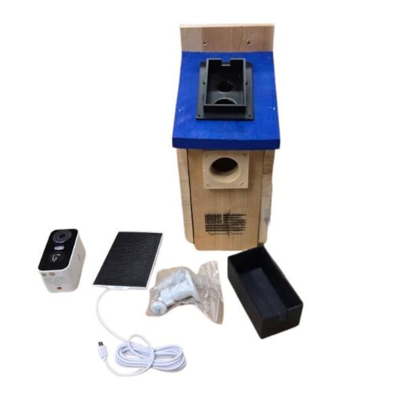 Puede incluir: Una casa para p&aacute;jaros de madera con techo azul y un orificio de entrada redondo. La casa para p&aacute;jaros va acompa&ntilde;ada de una c&aacute;mara, un panel solar, accesorios de montaje y una bandeja negra. La casa para p&aacute;jaros tiene un peque&ntilde;o dise&ntilde;o de bandera estadounidense.