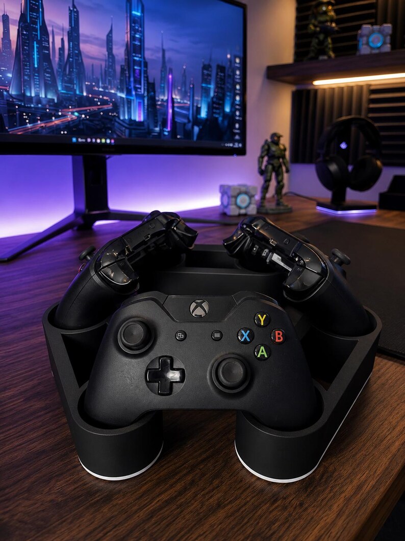 May include: A black plastic charging stand holding three black wireless game controllers. The front controller features a central Xbox logo, a directional pad, two analog sticks, and four colored action buttons labeled A, B, X, and Y.