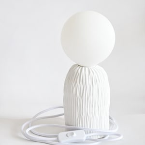 Lampe de table artisanale en céramique blanche, un objet décoratif et lumineux.