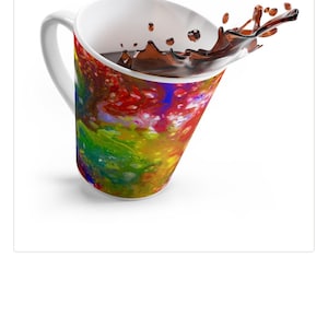 May include: A white ceramic mug with a colorful abstract design in red, yellow, green, and blue. The mug is tilted, with liquid splashing out. The mug has a white handle and interior.