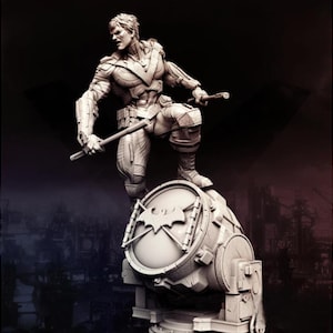 Può includere: Statua dettagliata di un personaggio di supereroe, con due bastoni, in piedi su una grande struttura rotonda con un simbolo di pipistrello. La figura è in posa dinamica, con intricati dettagli dell'armatura. Lo sfondo è una città industriale scura.