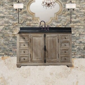 May include: A bathroom vanity with a black countertop and a white wood cabinet with drawers and doors. The vanity has a black faucet and a large ornate mirror above it. Two wall sconces with white shades are on either side of the mirror.