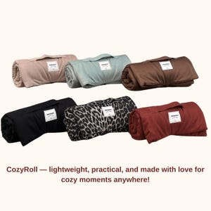 May include: Rolled blankets in various colors, including tan, teal, brown, black, leopard print, and red. Each blanket has a handle and a white label. The text "CozyRoll" is displayed below the blankets.