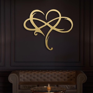 Puede incluir: Una obra de arte mural de metal dorado con forma de corazón entrelazado con un símbolo de infinito. La obra de arte está montada en una pared oscura sobre un sofá de cuero marrón y una mesa de centro con tapa de cristal.