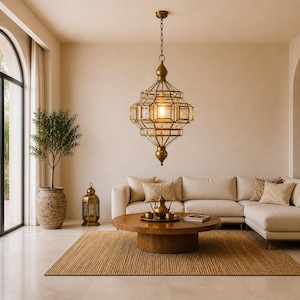 Pode incluir: Uma luminária pendente dourada, com design geométrico, está pendurada sobre uma sala de estar. A luz tem um design de vidro transparente e é suspensa por uma corrente. O quarto apresenta uma paleta de cores neutras com um sofá, mesa de centro e tapete.