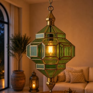 May include: A green and gold geometric pendant light fixture with a warm, glowing bulb. The lamp has a vintage aesthetic, with a brass chain and decorative accents. The design is reminiscent of a lantern, suitable for interior decor.