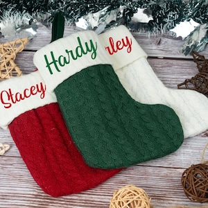 Puede incluir: Tres calcetines navideños personalizados en rojo, verde y blanco, con los nombres "Stacey", "Hardy" y "Harley" bordados en los puños. Los calcetines son de punto y están decorados con adornos festivos.