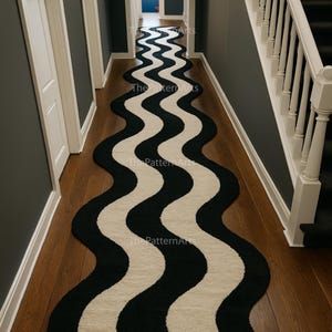 Può includere: Un lungo tappeto ondulato con un motivo nero e crema. Il tappeto è posto in un corridoio con pareti grigio scuro e pavimenti in legno. Il design del tappeto crea un flusso visivo lungo il corridoio.