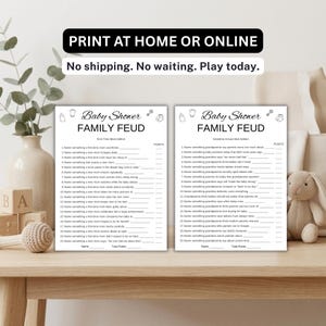 May include: Two white paper game sheets titled Baby Shower FAMILY FEUD. The left sheet is the First-Time Mom Edition and the right sheet is the Grandma Knows Best Edition. Both feature twenty numbered questions with blank lines for points.