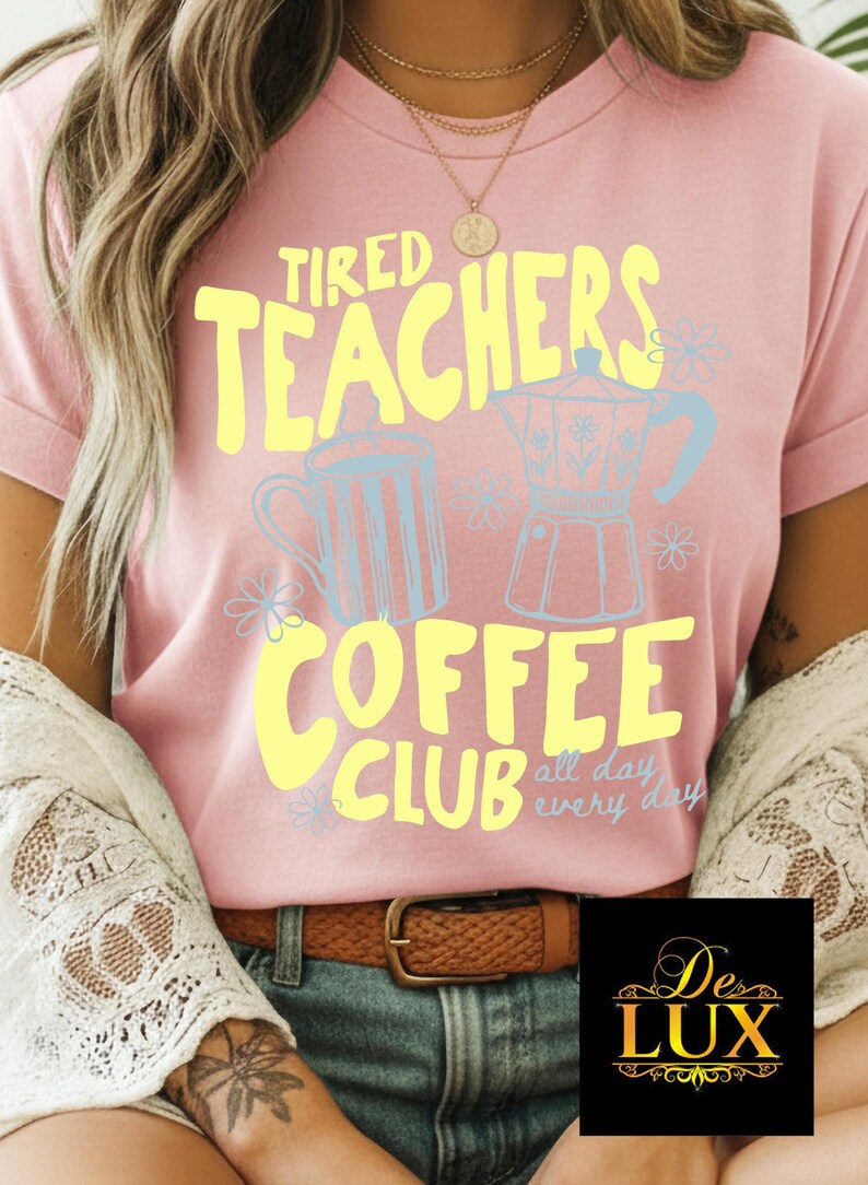 K&ouml;nnte beinhalten: Rosafarbenes T-Shirt mit dem Text "Tired Teachers Coffee Club" in Gelb, mit hellblauen Kaffee-Grafiken. Der Satz "all day every day" steht unter dem Club-Text. Ein brauner G&uuml;rtel und blaue Jeans sind sichtbar.