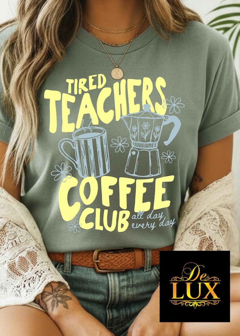 K&ouml;nnte beinhalten: Salbeigr&uuml;nes T-Shirt mit dem Text "Tired Teachers Coffee Club" in Gelb. Das Design umfasst eine Kaffeetasse und einen Espressokocher in Hellblau, mit floralen Akzenten. Der Satz "all day every day" ist ebenfalls enthalten.