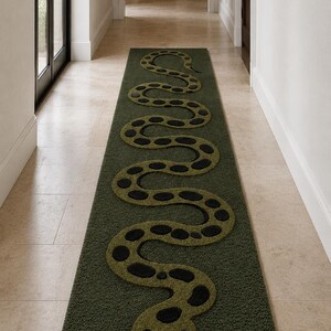 May include: A long, rectangular runner rug in a deep olive green shade. The rug features a raised, textured design of a winding snake in a lighter lime green colour, accented with dark black circular spots along its body and a black forked tongue.