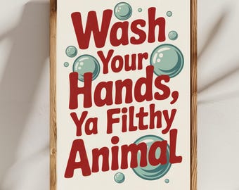 May include: A framed print with the text "Wash Your Hands, Ya Filthy Animal" in red, with teal bubbles. The print has a cream background and is in a wooden frame.