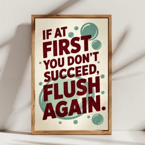 Pode incluir: Um poster emoldurado com um design vintage. O poster apresenta o texto "IF AT FIRST YOU DON'T SUCCEED, FLUSH AGAIN" em letras bordô. Bolhas verde-azuladas e um fundo creme completam o design. A moldura é de madeira.