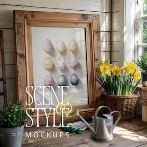 May include: A framed print of watercolour Easter eggs in pastel shades. The wooden frame is on a wooden surface, with a watering can, gardening gloves, and a potted plant. The words "SCENE STYLE MOCKUPS" are visible.