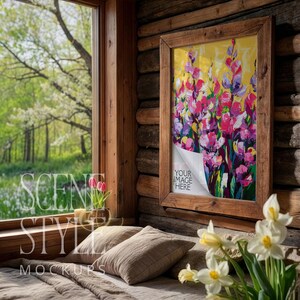 Puede incluir: Una obra de arte enmarcada con una pintura floral en tonos rosas, morados y amarillos cuelga de una pared de madera rústica. La obra de arte está en un marco de madera. El texto "YOUR IMAGE HERE" es visible. La escena incluye una ventana con vista a un bosque.