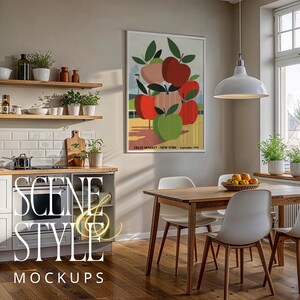 May include: A framed vintage poster featuring a cluster of apples in shades of red, green, and pink, with green leaves. The poster is displayed in a bright, modern kitchen setting with a wooden dining table and white chairs. The text "FRUIT MARKET - NEW YORK - September 1938" is visible.
